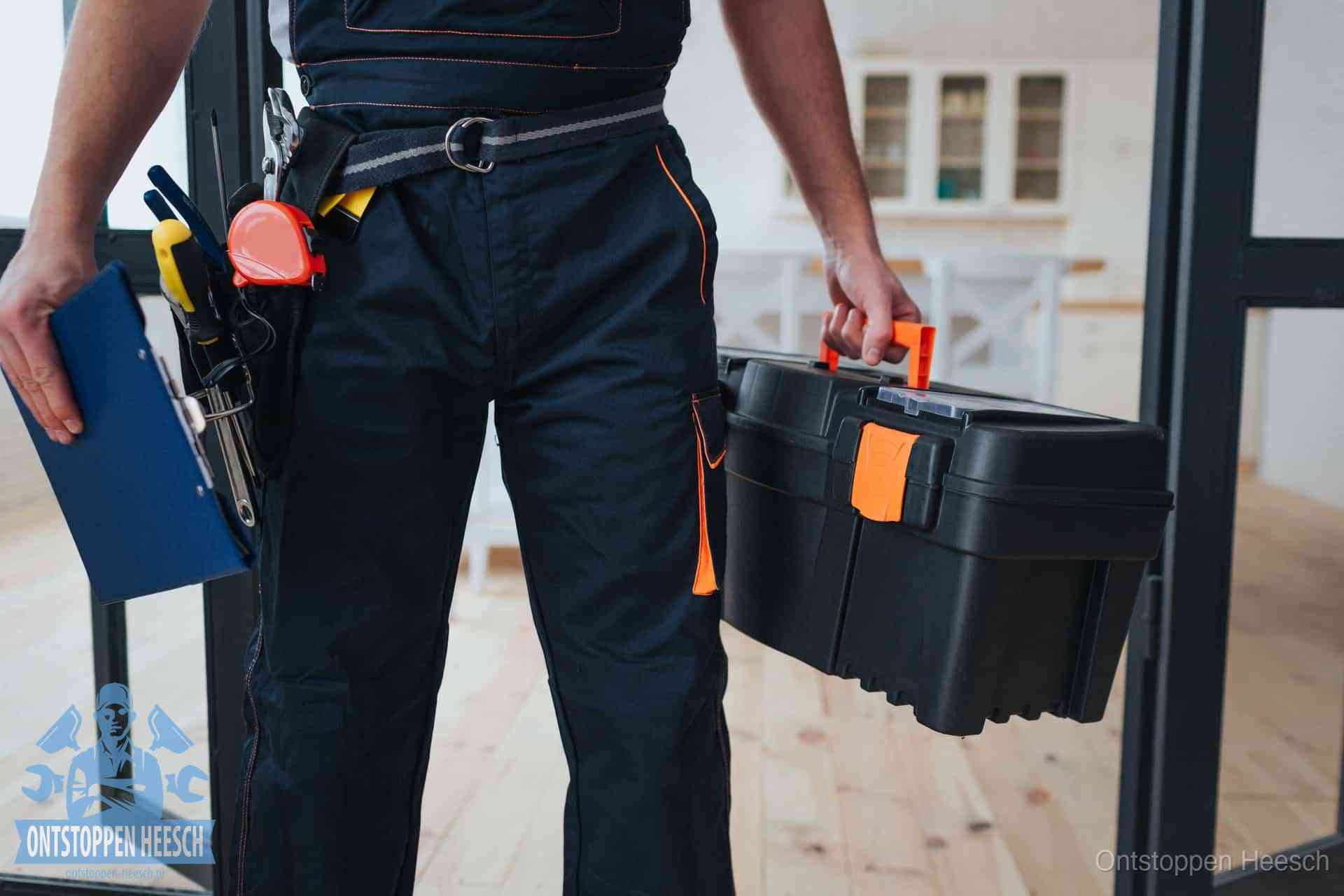 Een monteur met gereedschapsriem en klembord in een keuken, klaar om een transparante prijs voor het gootsteen ontstoppen in Heesch te geven