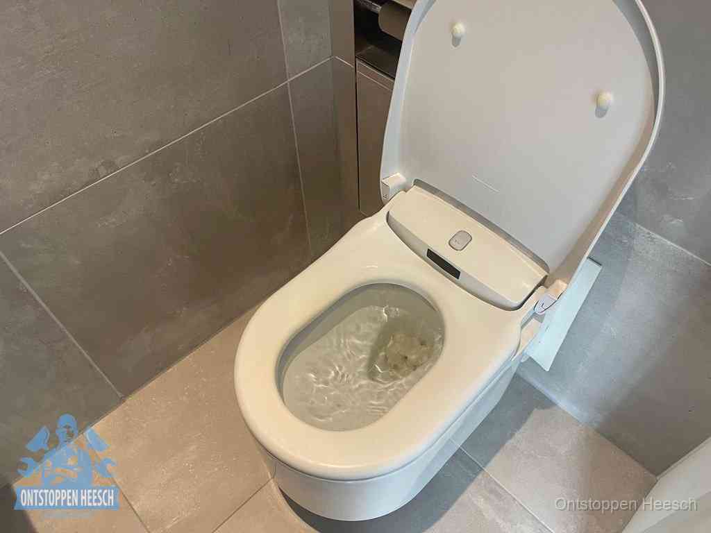 Een toiletpot vol troebel water met drijvend papier en restanten, de meest voorkomende oorzaak van een verstopte wc in Heesch