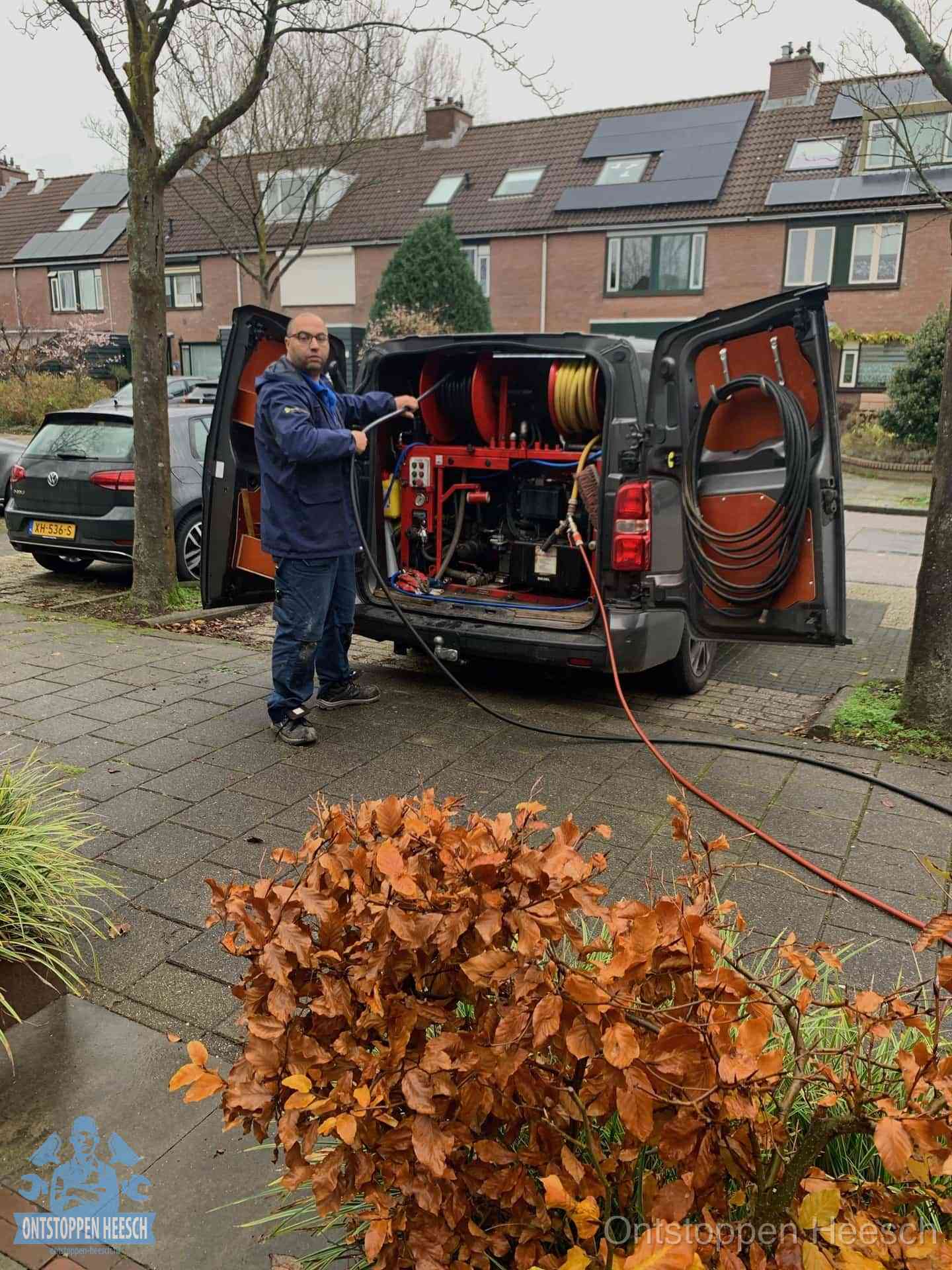 Monteur met rioolreinigingsbus levert rioolservice in de wijk in Heesch