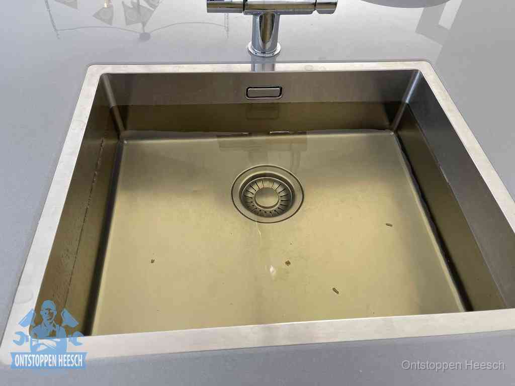 Stilstaand water in een rvs spoelbak dat niet wegloopt, een duidelijk signaal van een gootsteenverstopping in Heesch