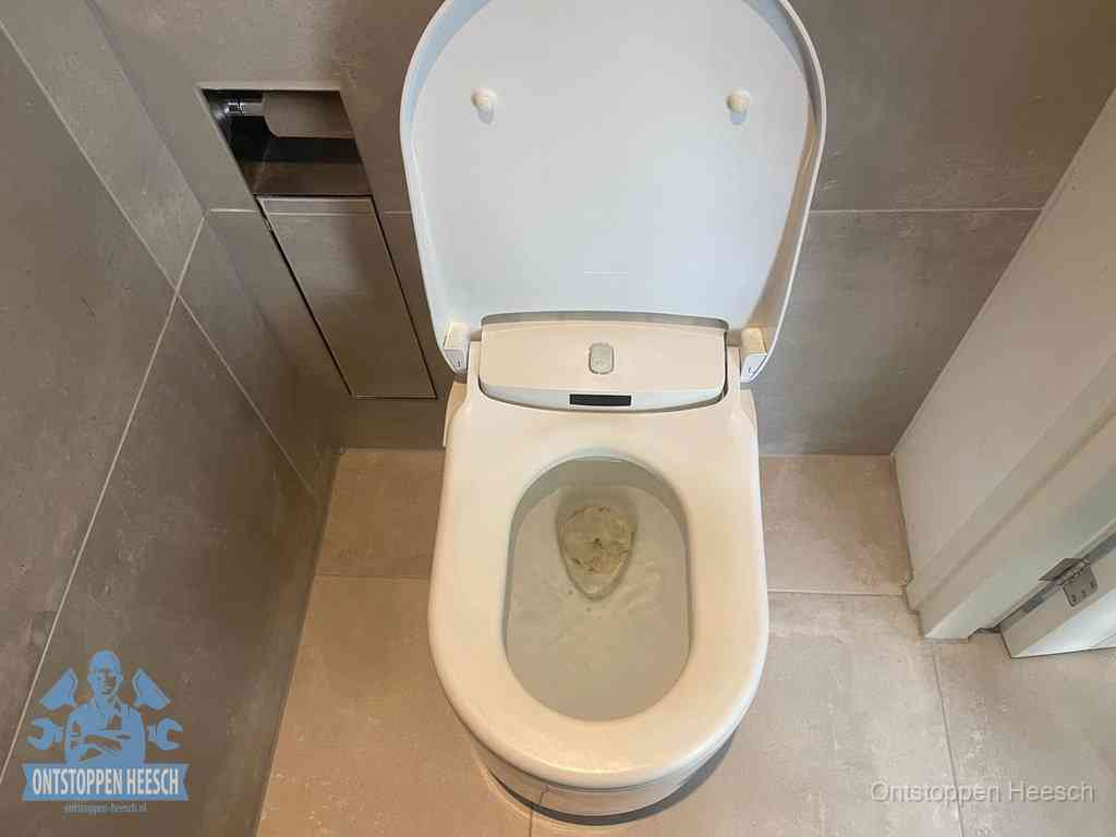 Een wit hangtoilet waarin een prop wc-papier op het water blijft drijven, een duidelijk signaal van een verstopte wc in Heesch