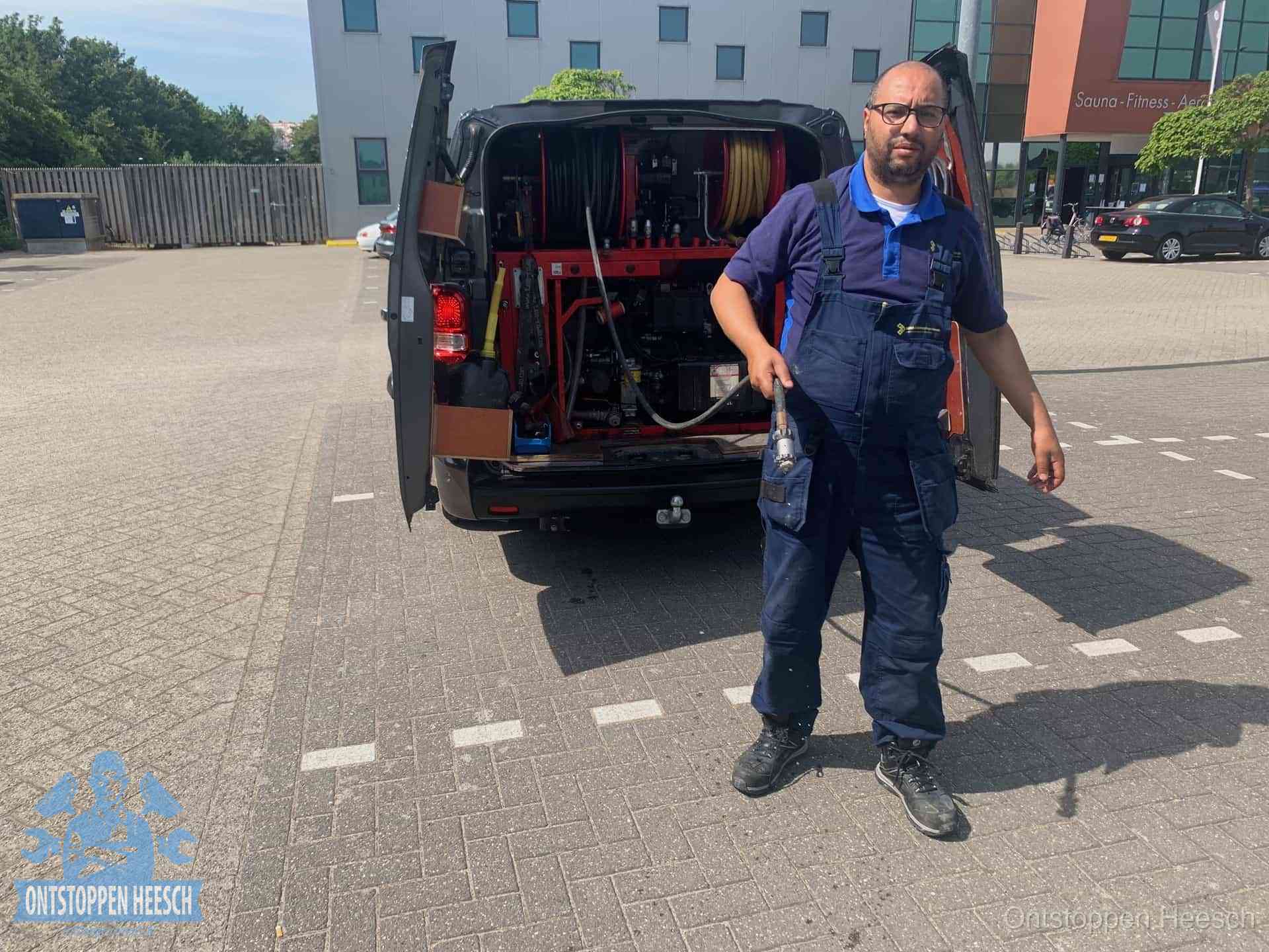 Een monteur bij zijn bestelbus met een hogedruk- en rioolreinigingsunit, klaar om de oorzaak van terugkerende wc-verstoppingen aan te pakken in Heesch