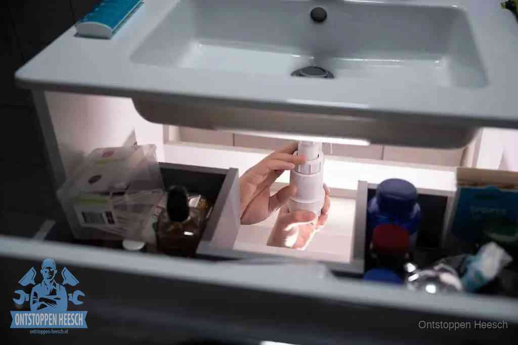 Een pompfles met zeep boven een wastafel in de toiletruimte, de warm water en afwasmiddel-methode om de wc te ontstoppen in Heesch