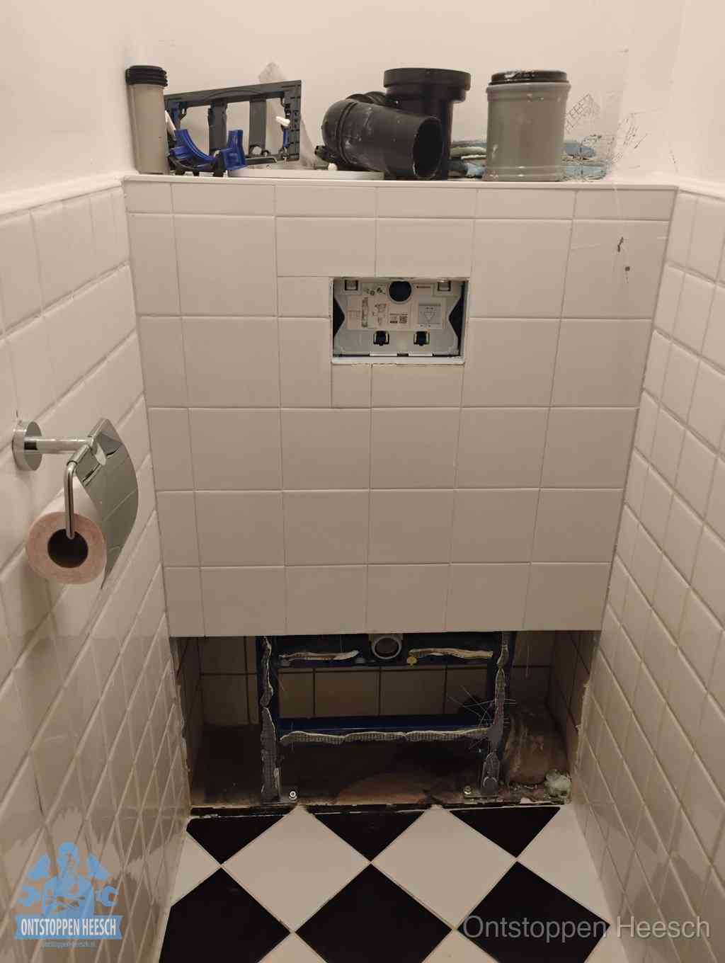 Een toiletruimte waar het hangtoilet en de inbouwreservoir-onderdelen zijn vrijgelegd voor onderhoud, periodiek nazicht voorkomt een wc-verstopping in Heesch
