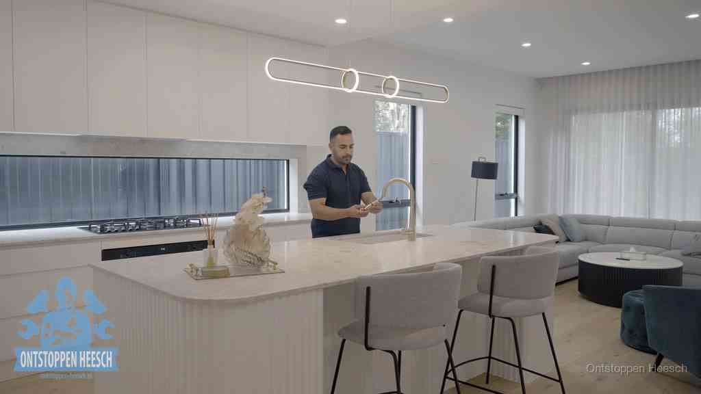 Een bewoner bij de keukenspoelbak die zelf aan de slag gaat met een verstopte gootsteen in Heesch